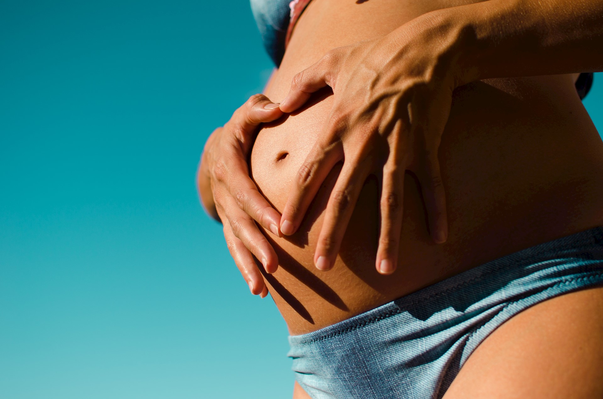 Zwangere vrouw met blote buik krijgt een zwangerschaps-massage in Groningen