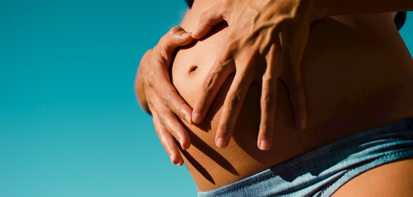 Zwangere vrouw met blote buik krijgt een zwangerschaps-massage in Groningen 