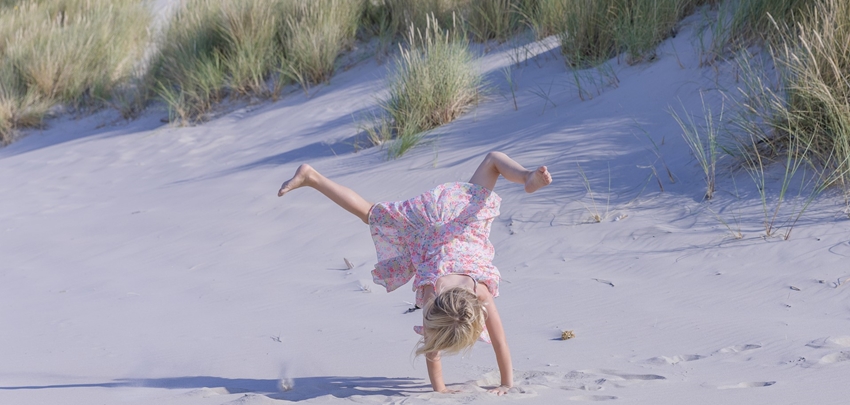Meisje doet handstand op het zandstrand van Ameland Meisje doet handstand op het zandstrand van Ameland