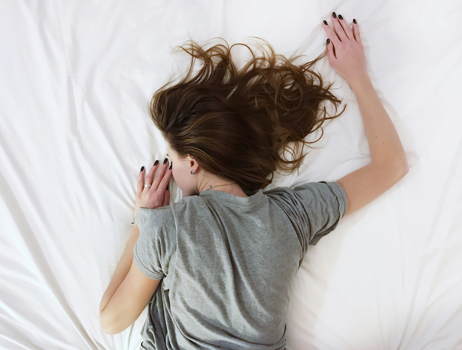 Vrouw ligt vermoeid op bed door stress en vermoeidheid 