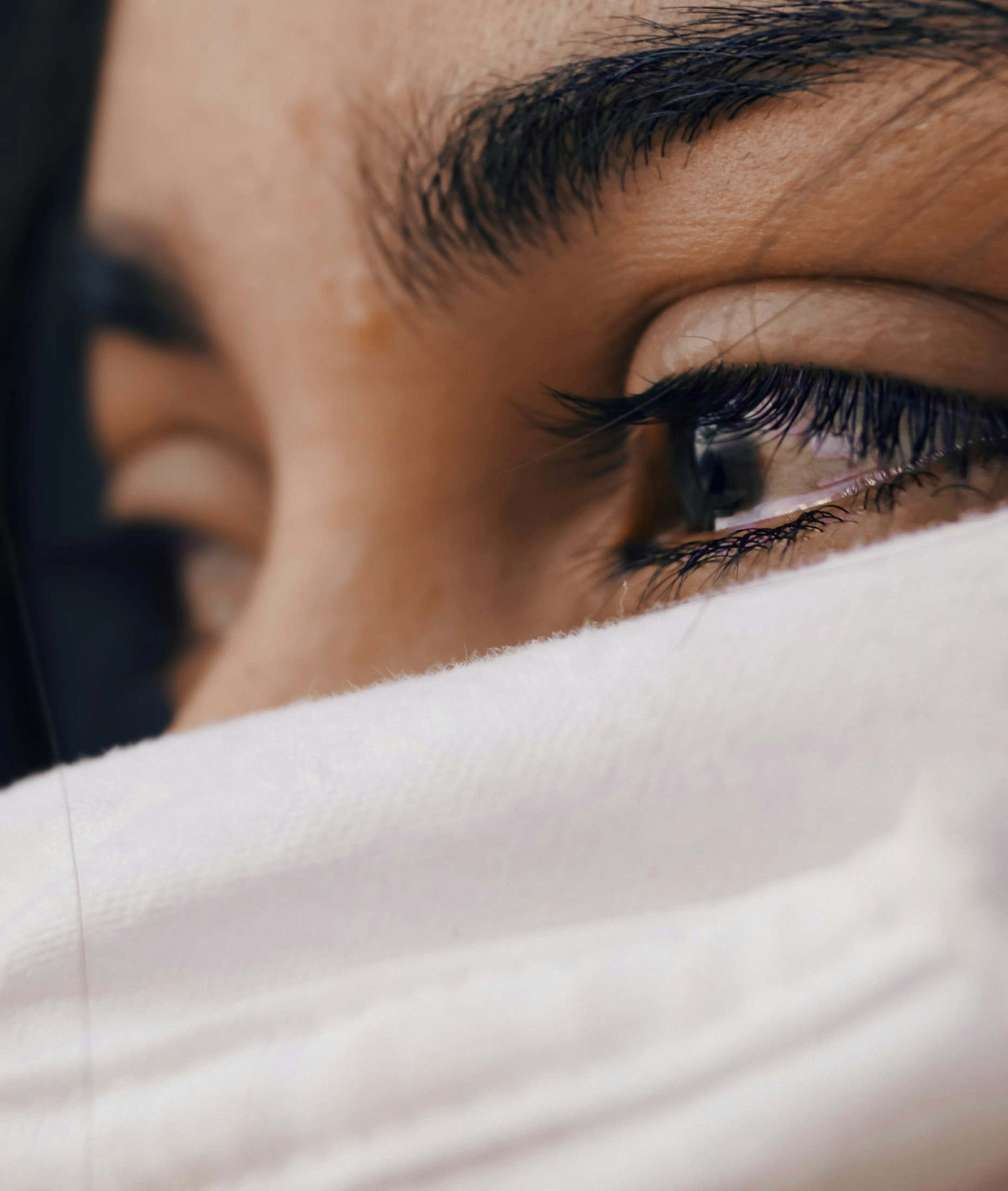 Vrouw met witte sjaal en tranen in haar ogen, emotionele uitdrukking van verdriet en rouw 